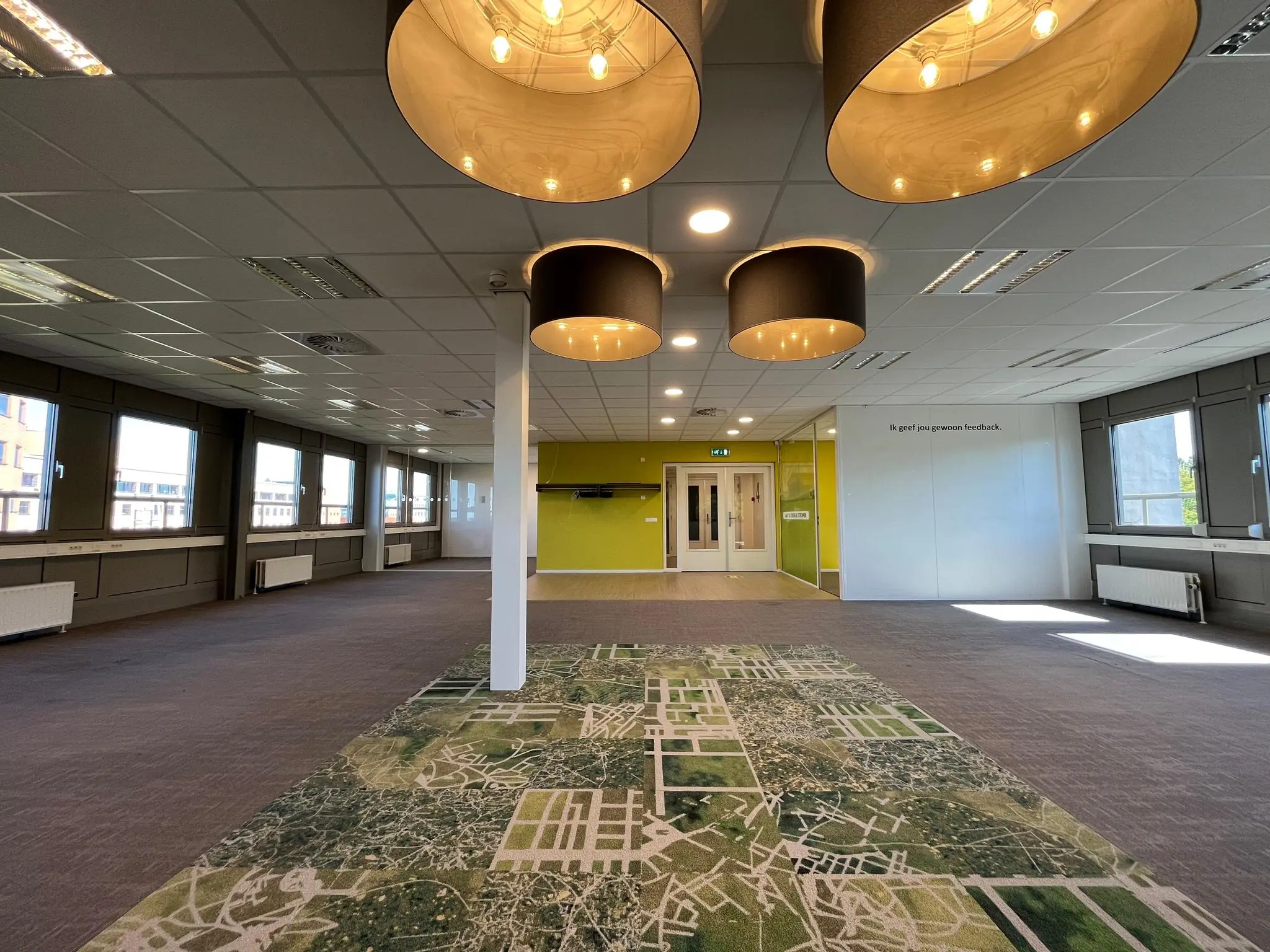 Lichte, moderne kantoorruimte aan de Barchman Wuytierslaan met opvallende hanglampen en een vloer met luchtfoto-patroon.